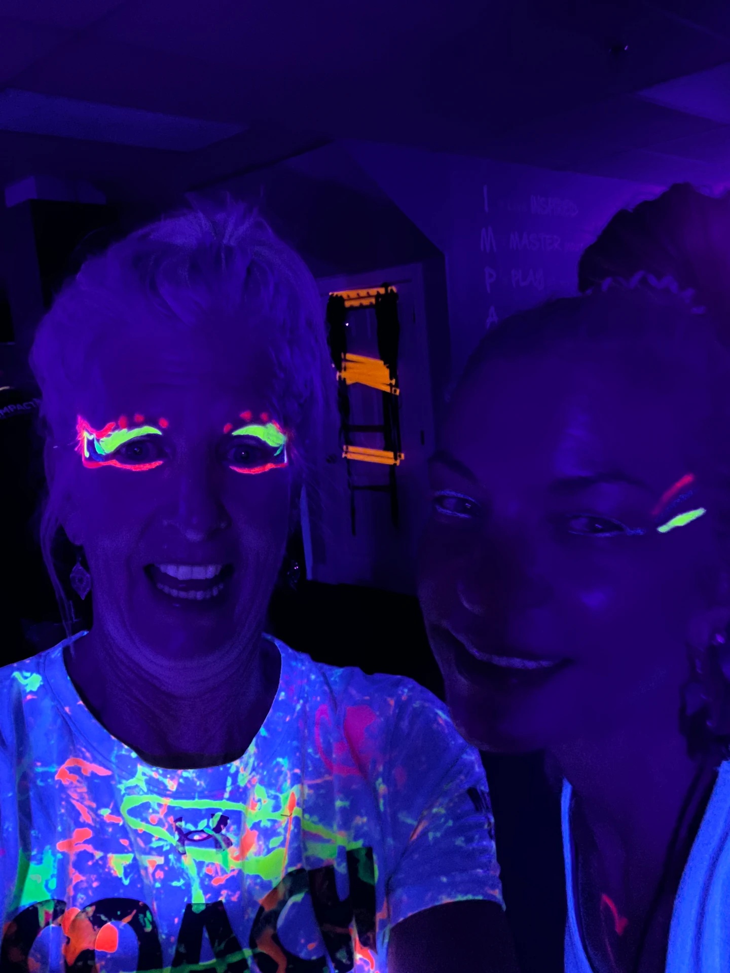 Two friends smiling with fluorescent face paint at a glow event